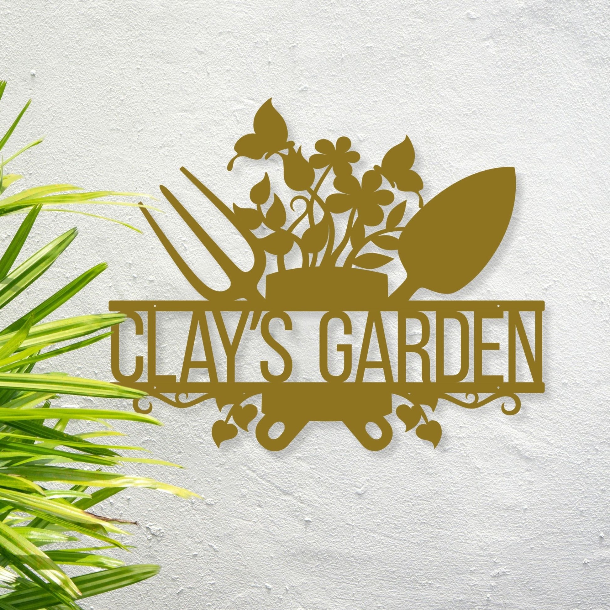Decorative metal sign with 'CLAY'S GARDEN' text and gardening tools on a textured white background.