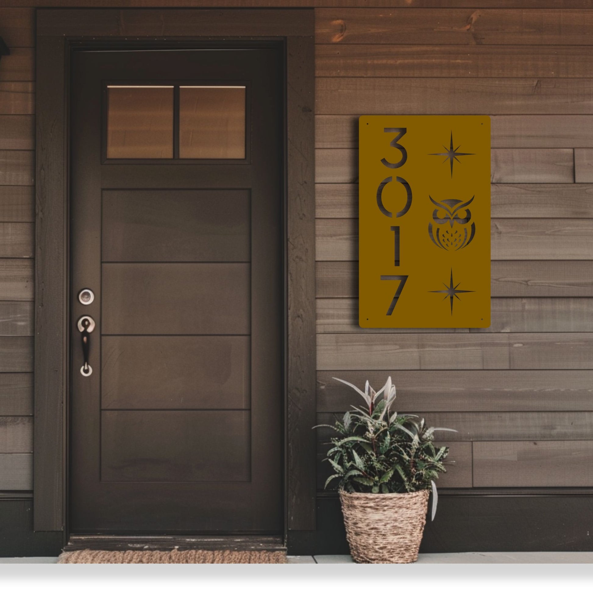 Front door of a house with a decorative address sign and potted plant.