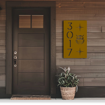 Front door of a house with a decorative address sign and potted plant.