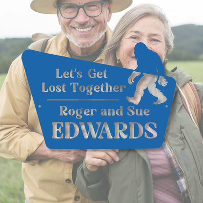 Two people holding a blue sign with text and a bear graphic, standing outdoors.