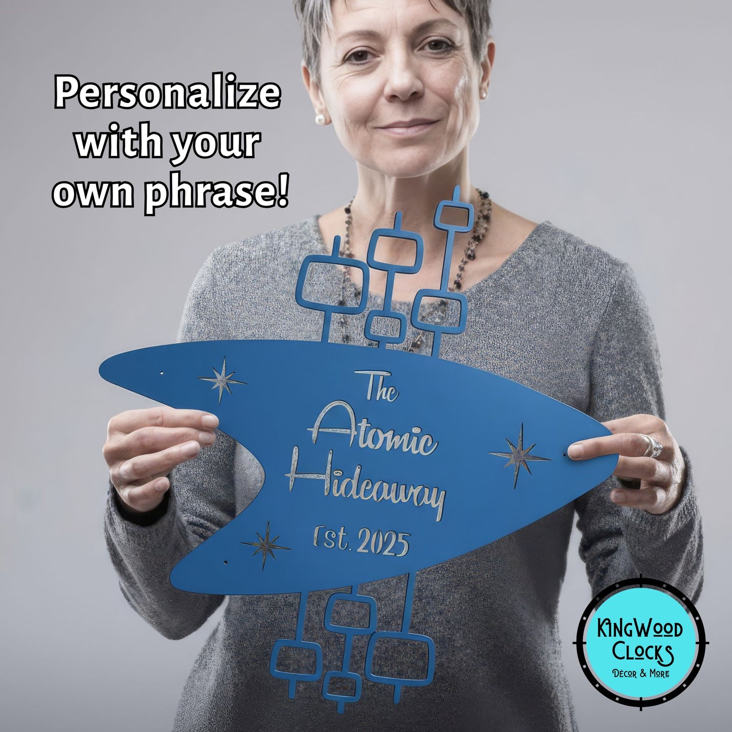 Woman holding a blue sign with 'The Atomic Hideaway' text, promotional image for Kingwood Clocks.