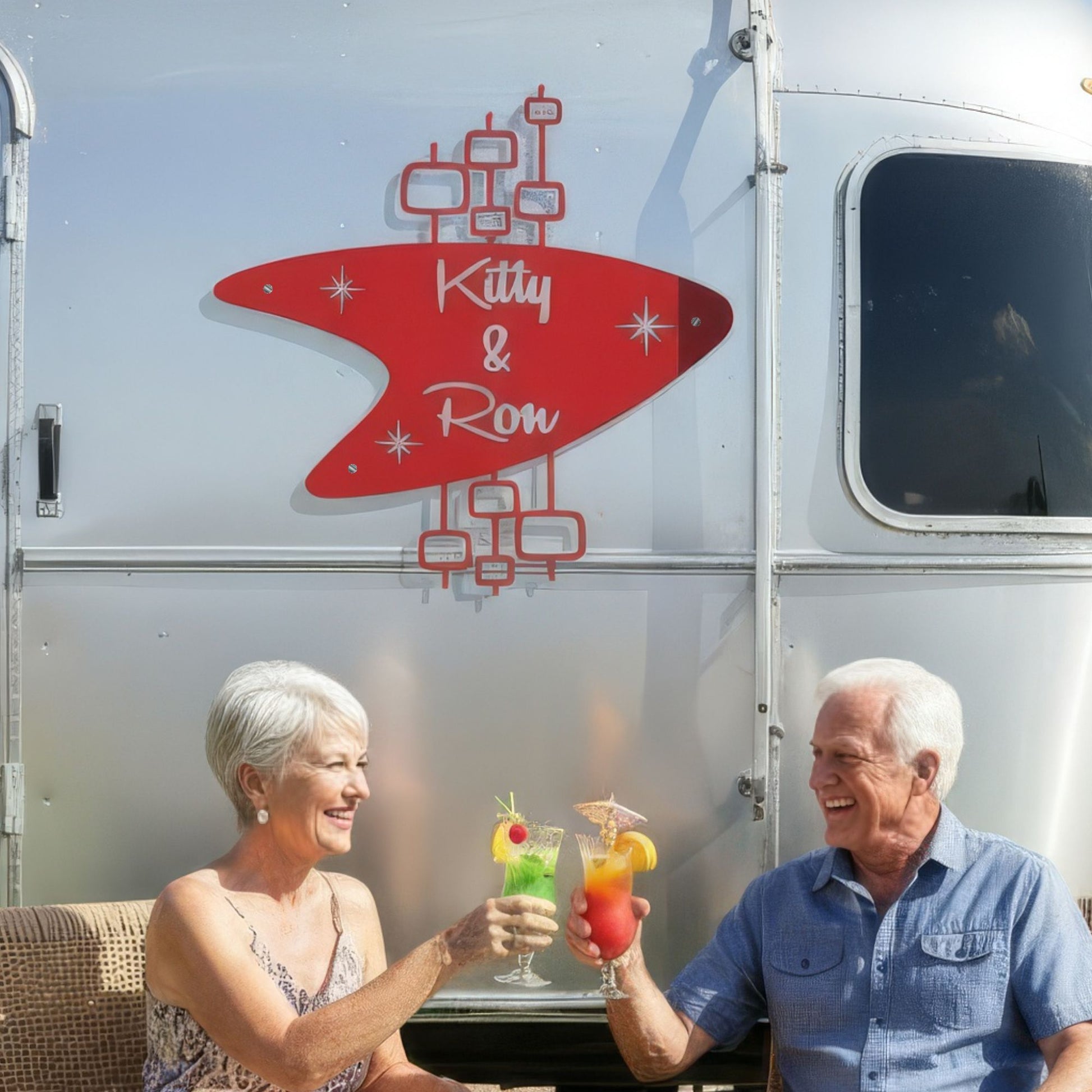 Two people sitting in front of a trailer with 'Kitty & Ron' branding
