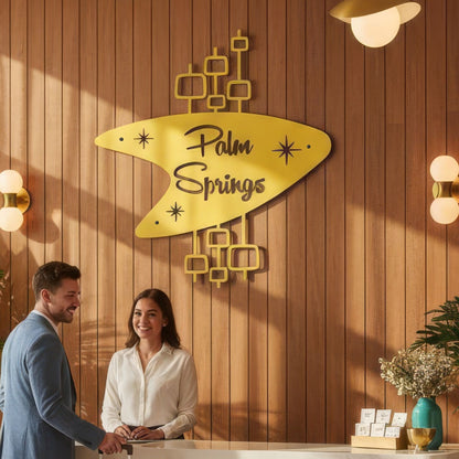 Two people standing in front of a 'Palm Springs' sign on a wooden wall.