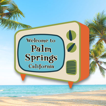 Vintage television sign with 'Welcome to Palm Springs California' text against a beach and palm tree background.