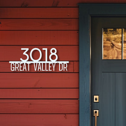 House number sign '3018 GREAT VALLEY DR' on a red wooden wall with a blue door.