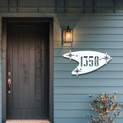 House exterior with a decorative metal address sign on a blue wall.