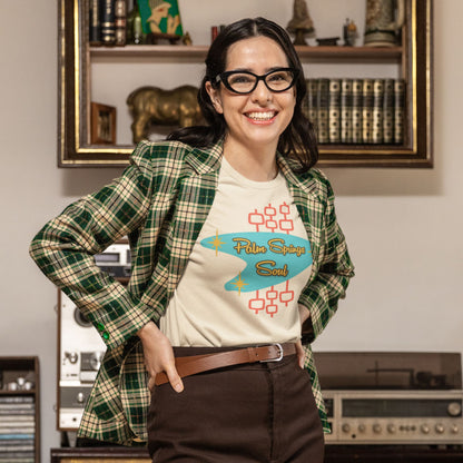 Woman wearing a plaid jacket and 'Palms Springs Soul' beige t-shirt in a room with vintage decor.