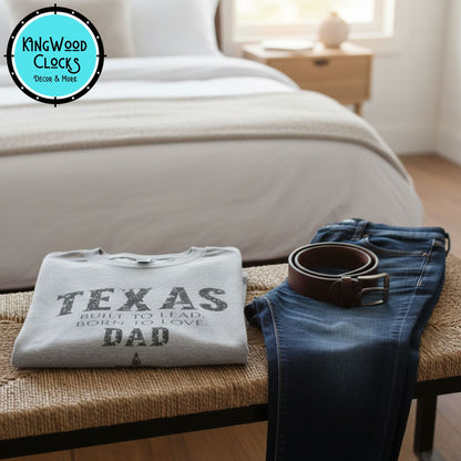 Gray sweatshirt with 'Texas Dad' text on a wooden bench in a bedroom.
