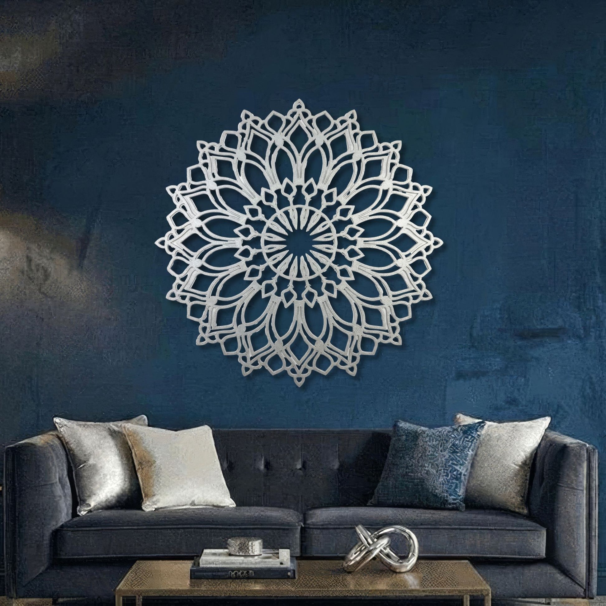 Decorative wall mandala on a blue wall above a gray sofa with cushions.