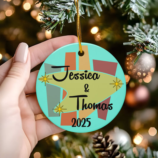 Decorative ornament with 'Jessica & Thomas 2025' text held in front of a Christmas tree.