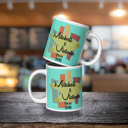 Two turquoise mugs with 'Mitchell & Victoria Since 2016' design on a wooden surface.
