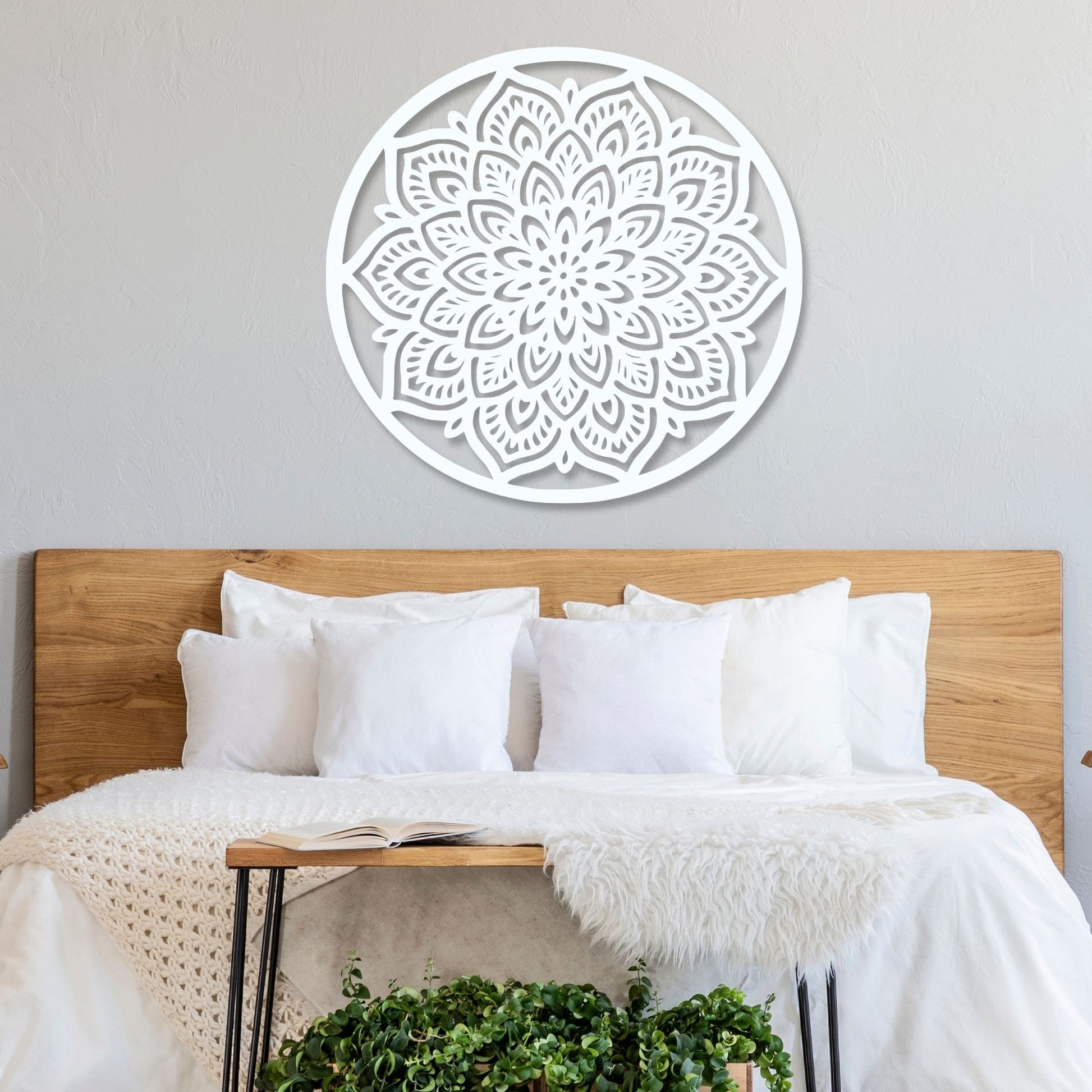 Decorative wall mandala above a bed with wooden headboard and white bedding.