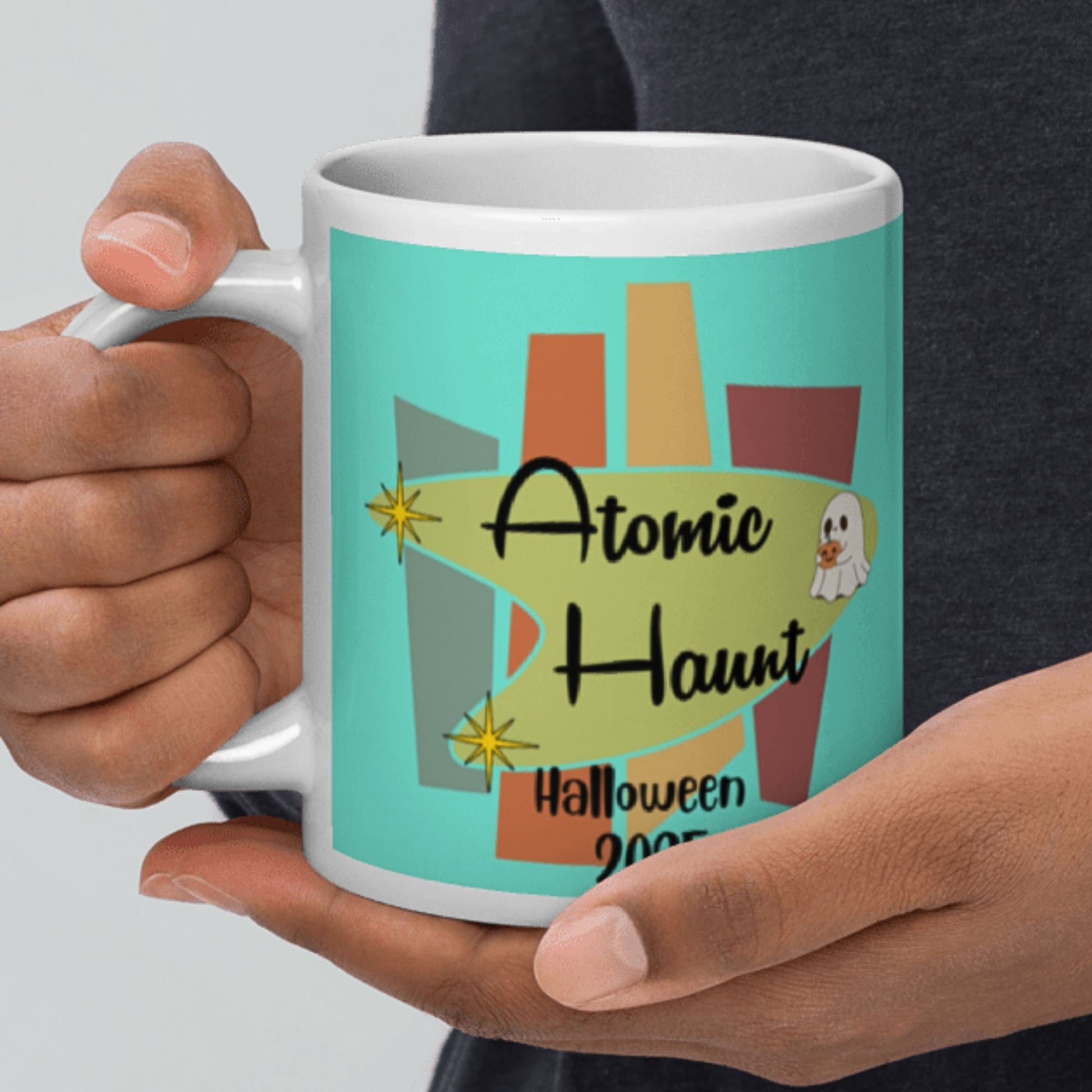 Person holding a mug with 'Atomic Haunt Halloween' design
