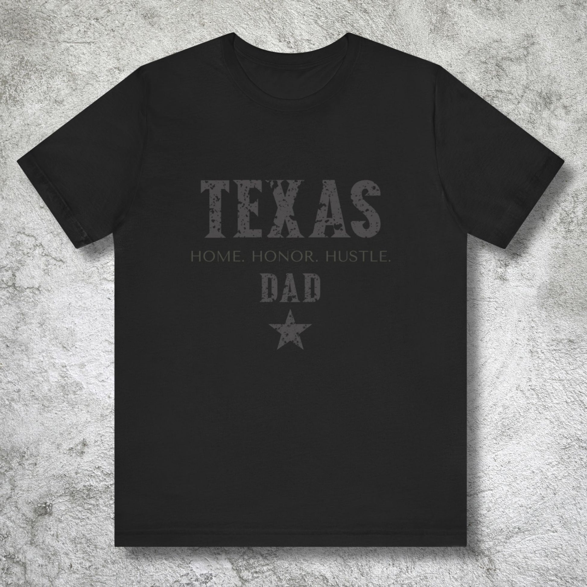 Black t-shirt with 'Texas Home Honor Hustle Dad' text on a textured gray background