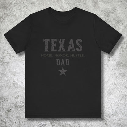 Black t-shirt with 'Texas Home Honor Hustle Dad' text on a textured gray background