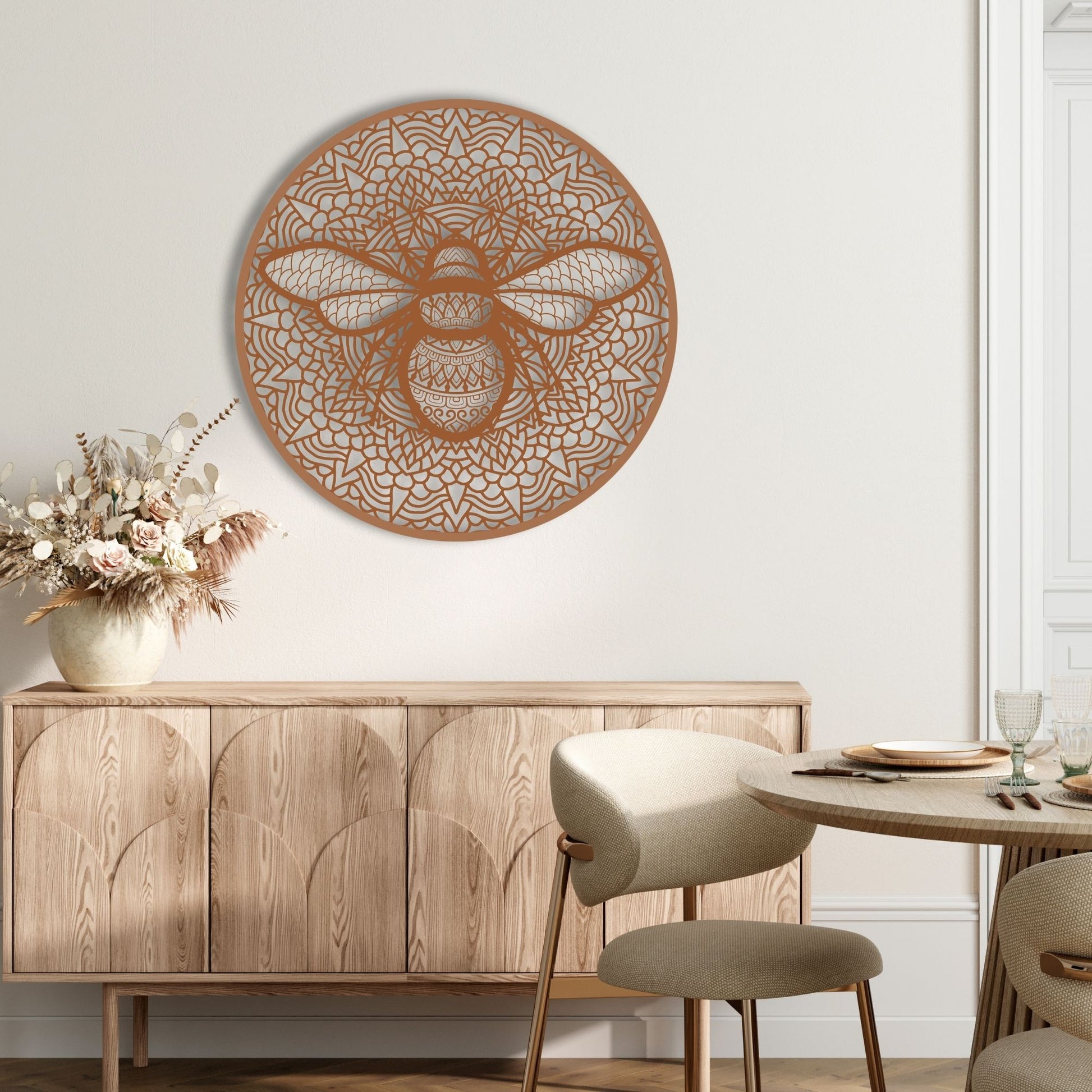 Decorative wall art of a bee on a white wall above a wooden cabinet.
