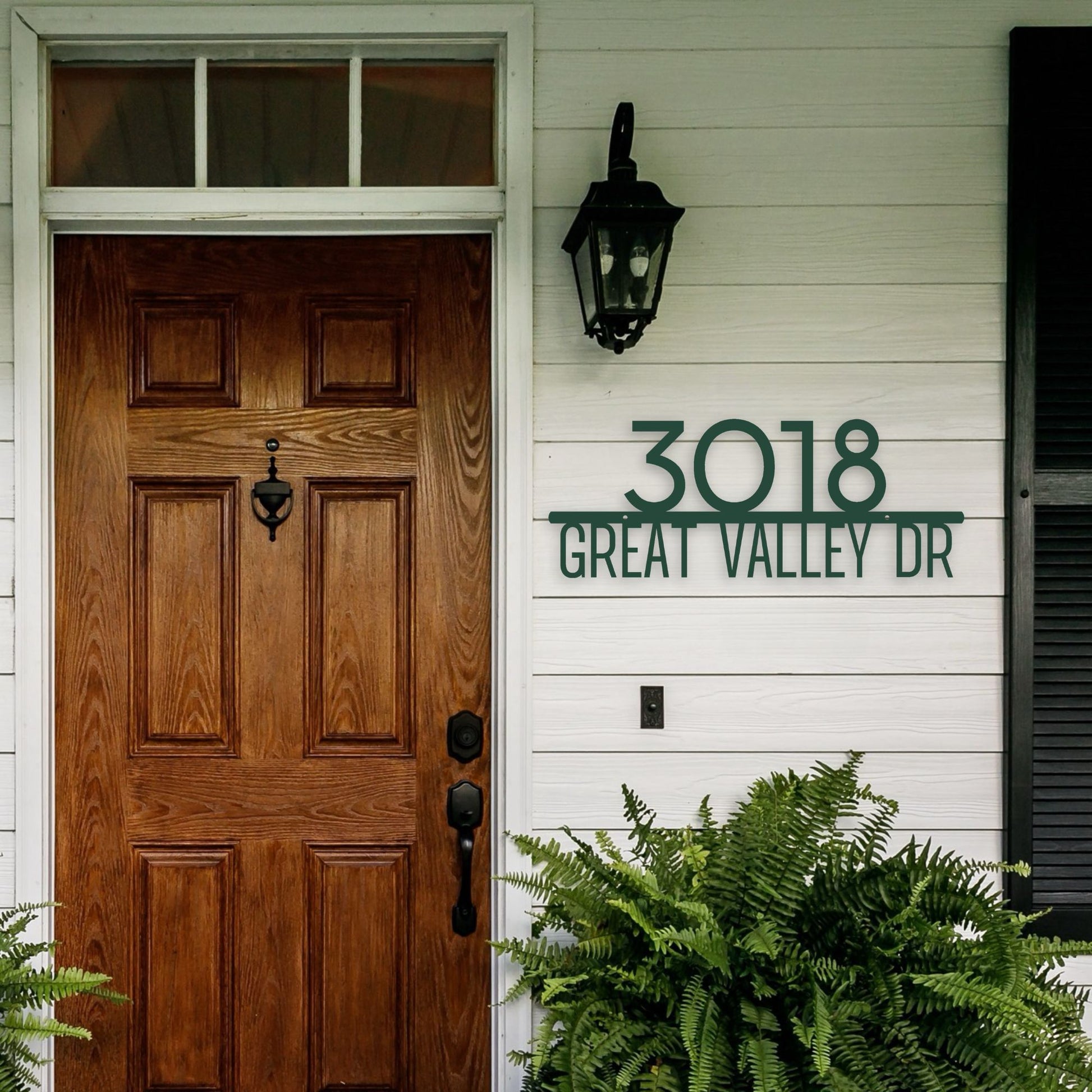 Wooden front door with address sign '3018 Great Valley Dr' on a white house exterior.