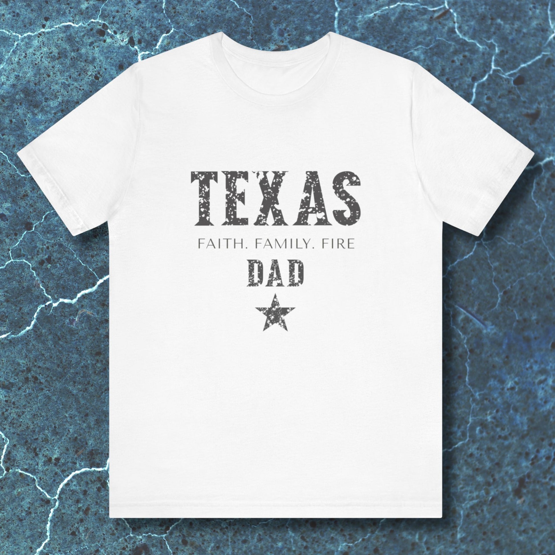 White t-shirt with 'TEXAS FAITH. FAMILY. FIRE DAD' text on a textured blue background
