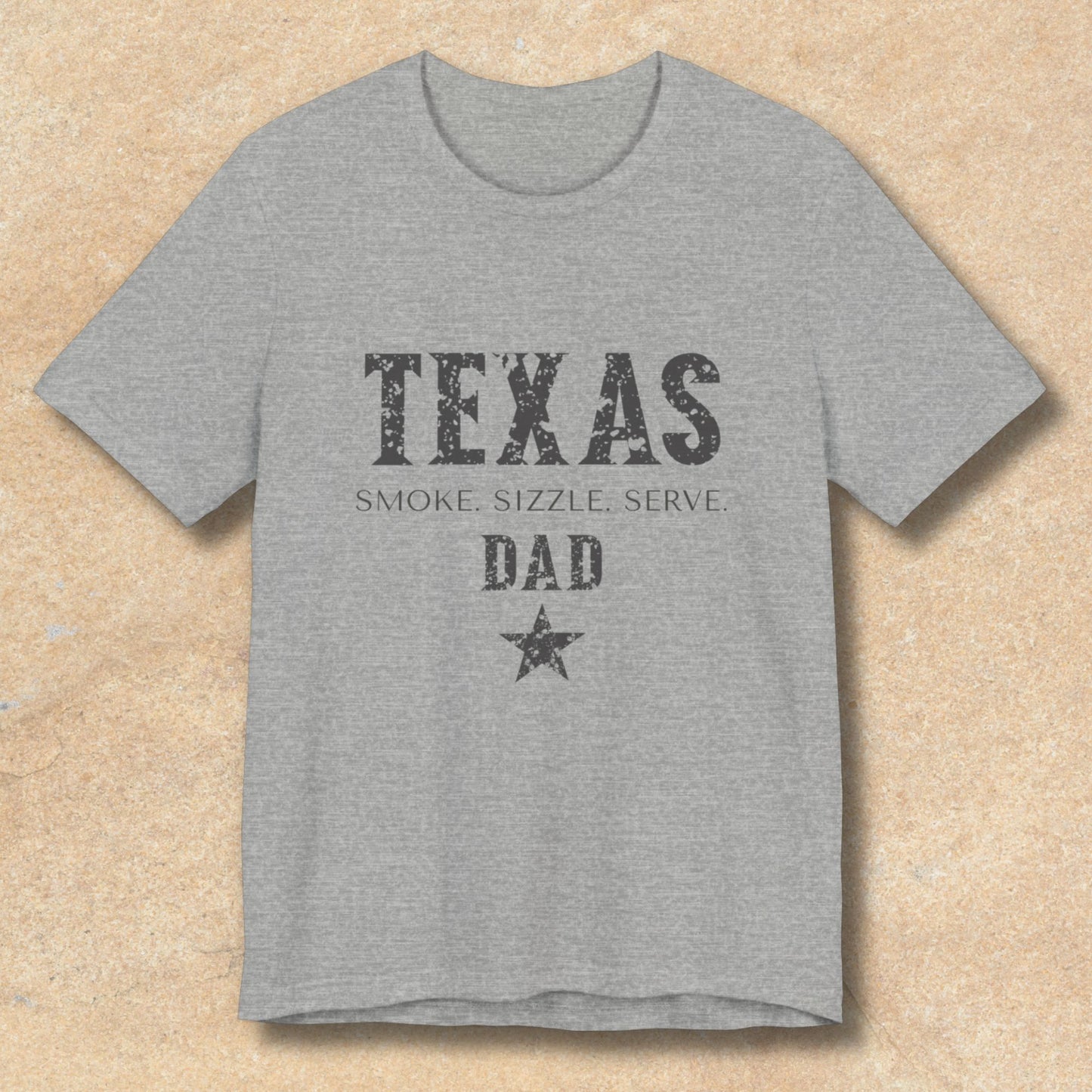 Gray t-shirt with 'Texas Smoke, Sizzle, Serve Dad' text on a beige background