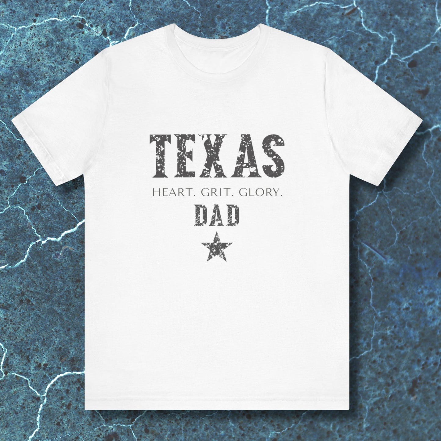 White t-shirt with 'TEXAS HEART, GRIT, GLORY DAD' text on a blue textured background