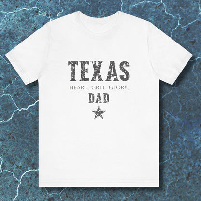 White t-shirt with 'TEXAS HEART, GRIT, GLORY DAD' text on a blue textured background