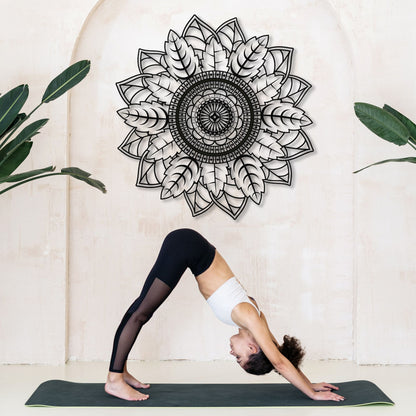 Person in a yoga pose on a mat with a decorative mandala wall art in the background.