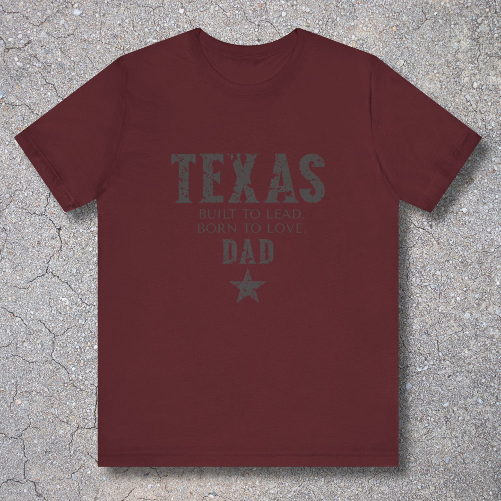 Maroon t-shirt with 'Texas Dad' text on a textured surface