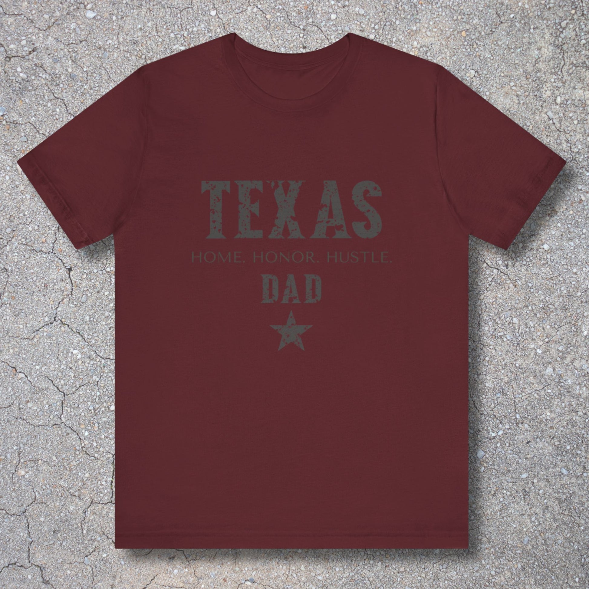 Maroon t-shirt with 'TEXAS HOME HONOR HUSTLE DAD' text on a textured surface