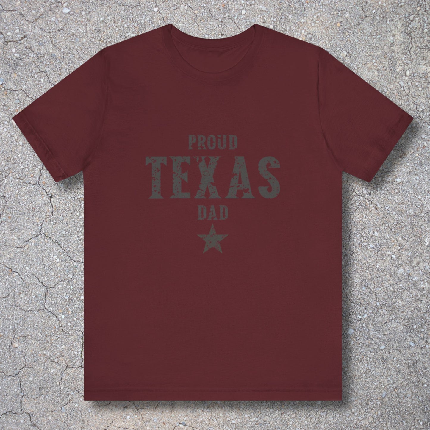 Maroon t-shirt with 'Proud Texas Dad' text on a textured surface