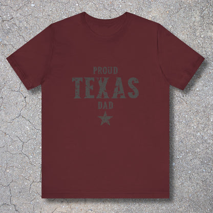 Maroon t-shirt with 'Proud Texas Dad' text on a textured surface