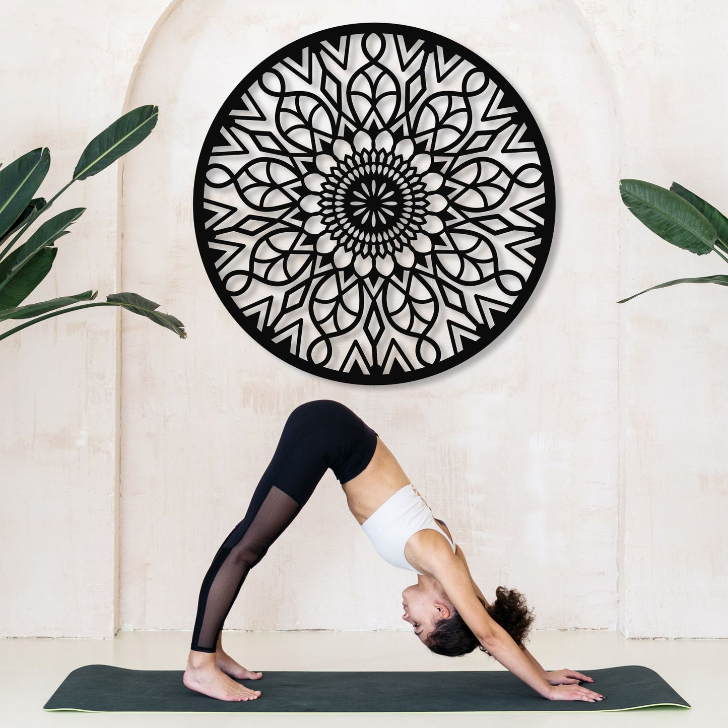 Person practicing yoga in front of a decorative wall art piece.