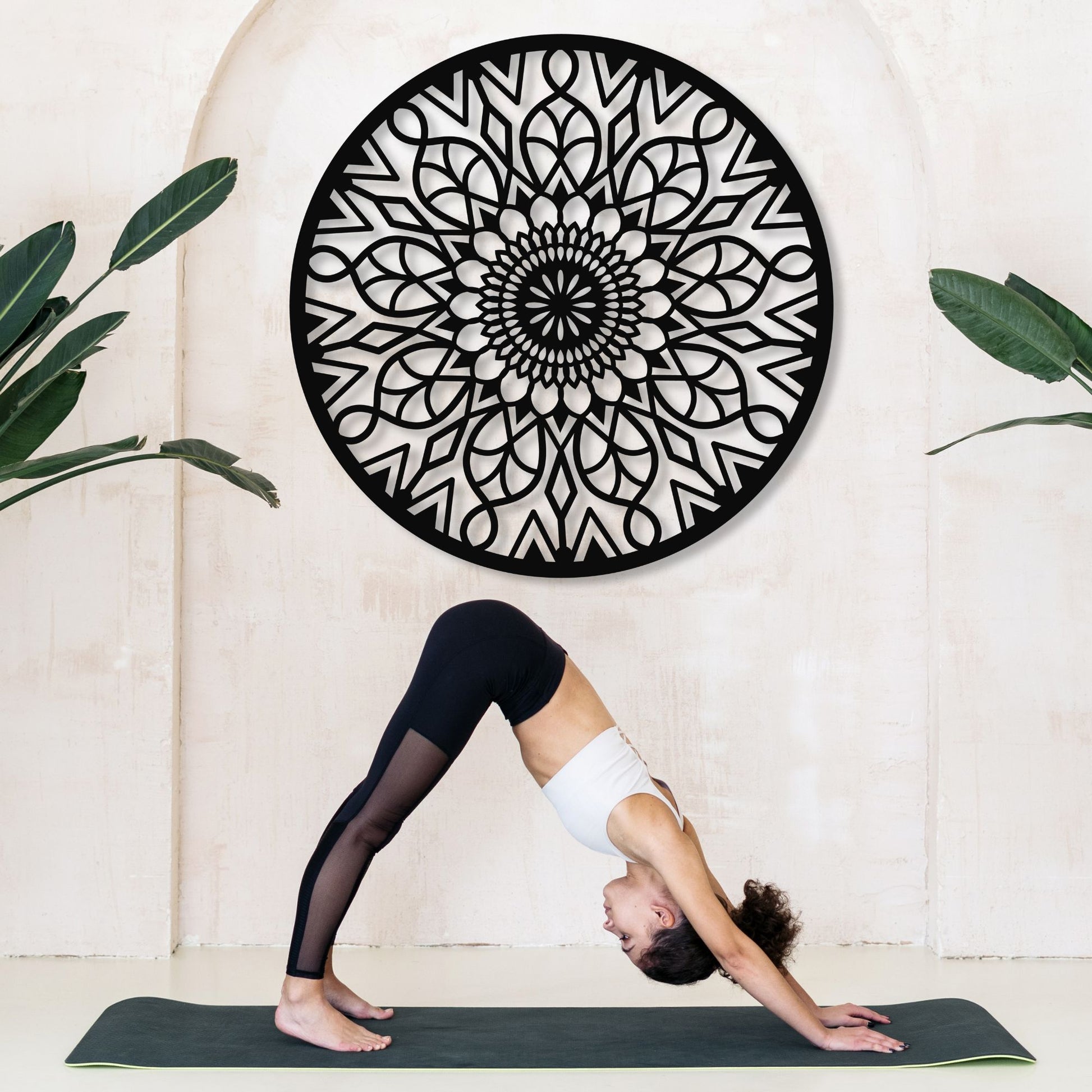 Person practicing yoga in front of a decorative wall art piece.