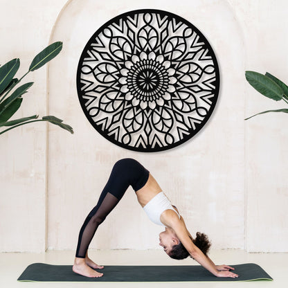 Person practicing yoga in front of a decorative wall art piece.