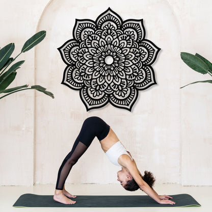 Person in a yoga pose on a mat with a decorative mandala wall art in the background.