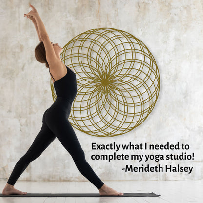 Woman in black yoga attire practicing yoga in a studio with a decorative wall piece.