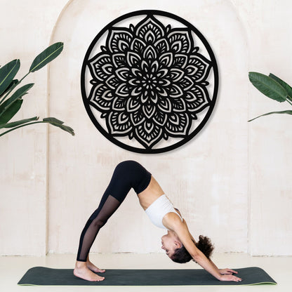 Person in a yoga pose on a mat with a decorative black mandala wall art in the background.