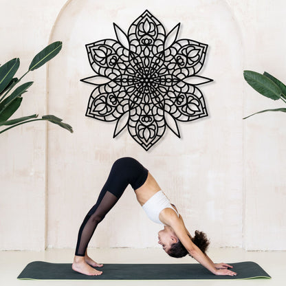 Person in a yoga pose on a mat with a decorative wall piece in the background