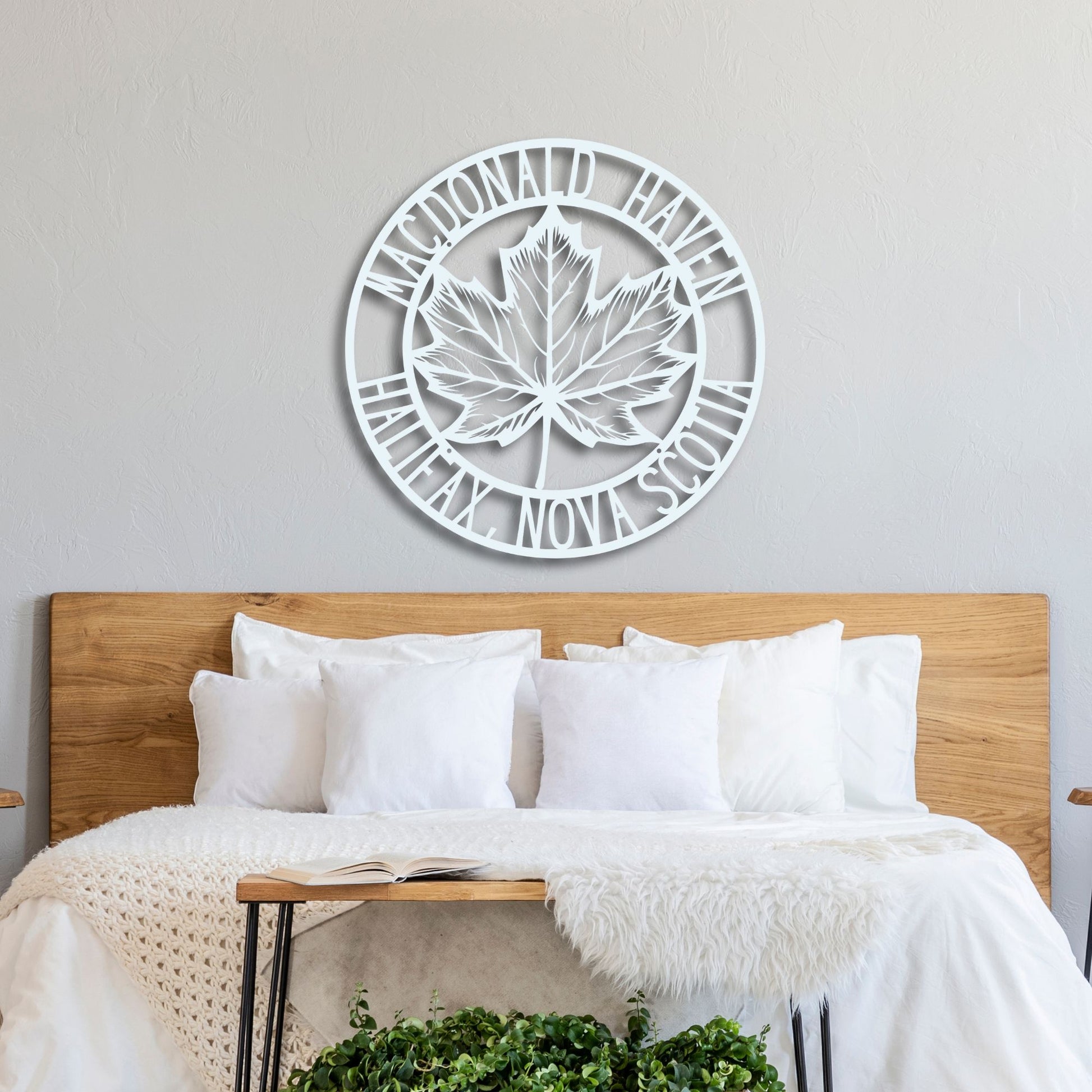 Decorative wall clock with a leaf design above a bed in a bedroom.