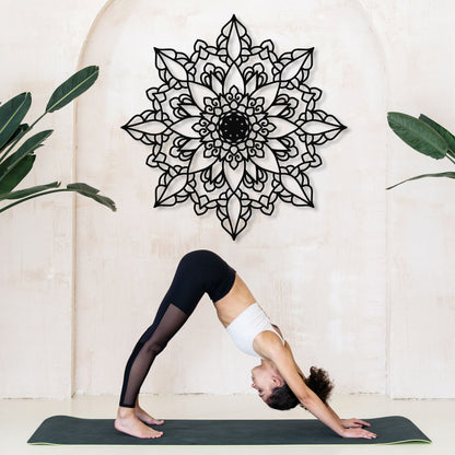 Person in a yoga pose on a mat with a decorative mandala wall art in the background.