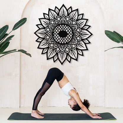 Person in a yoga pose on a mat with a decorative mandala wall art in the background.