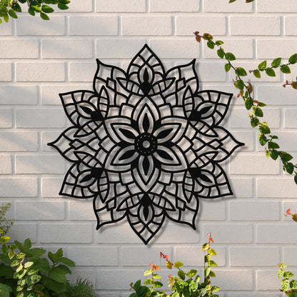 Decorative black metal wall art with floral pattern on a white brick wall.
