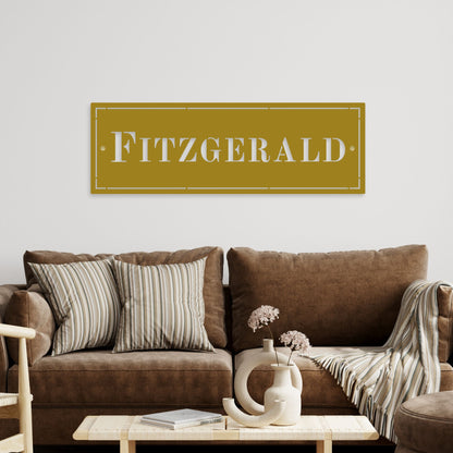 Brown sofa with decorative pillows and a coffee table in a living room setting, featuring a sign with 'Fitzgerald' on the wall.