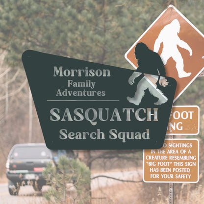 Sasquatch search squad sign with Bigfoot silhouette and road in background