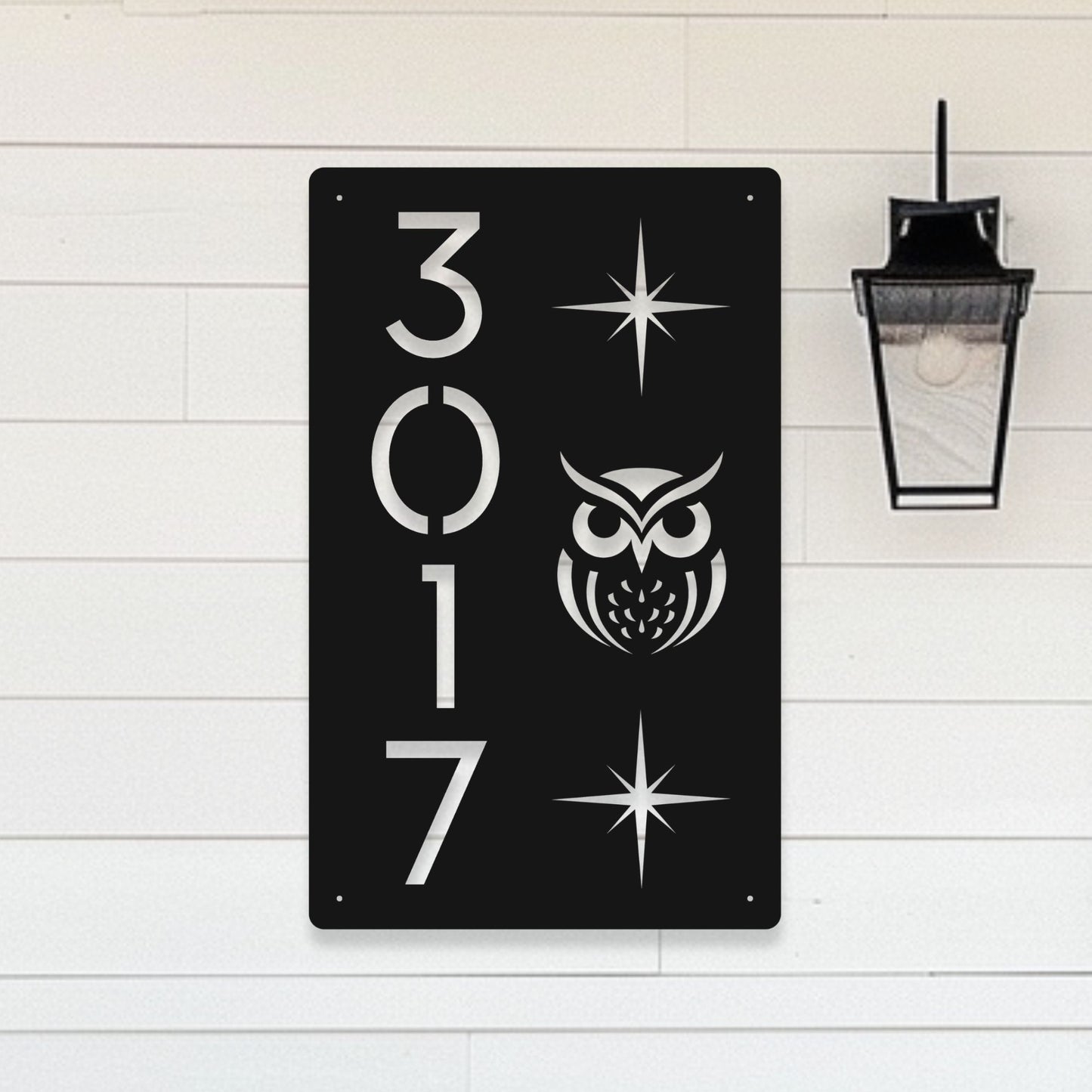 Black metal sign with white owl design and numbers '3017' on a light wooden background