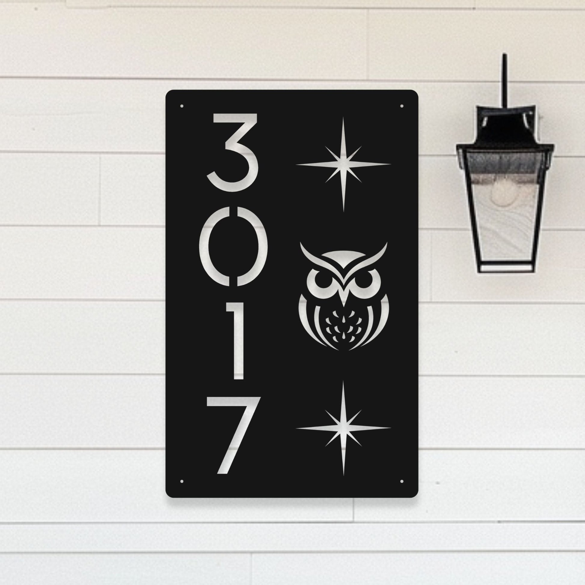 Black metal sign with white owl design and numbers '3017' on a light wooden background