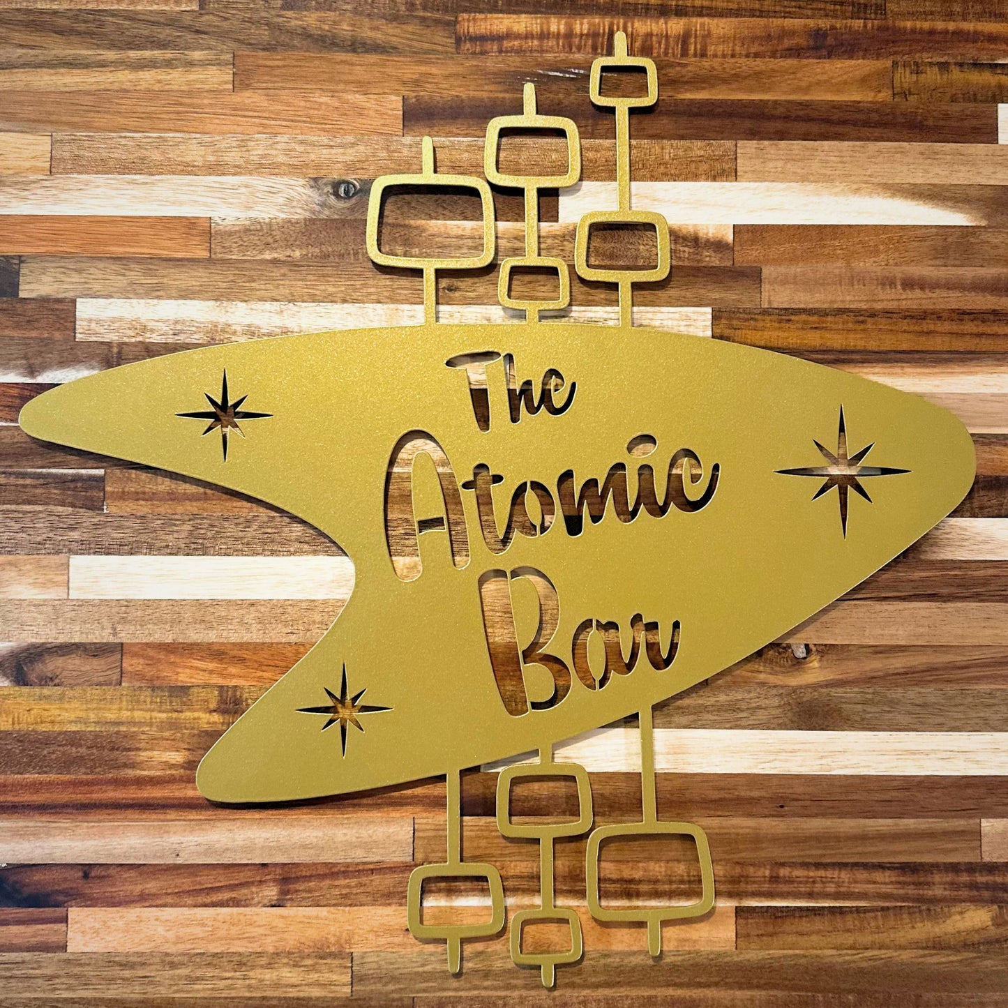 gold boomerang metal wall art with the atomic bar die cut into metal