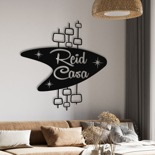 Personalized Mid Century Modern Name Sign shown in black hanging over living room couch