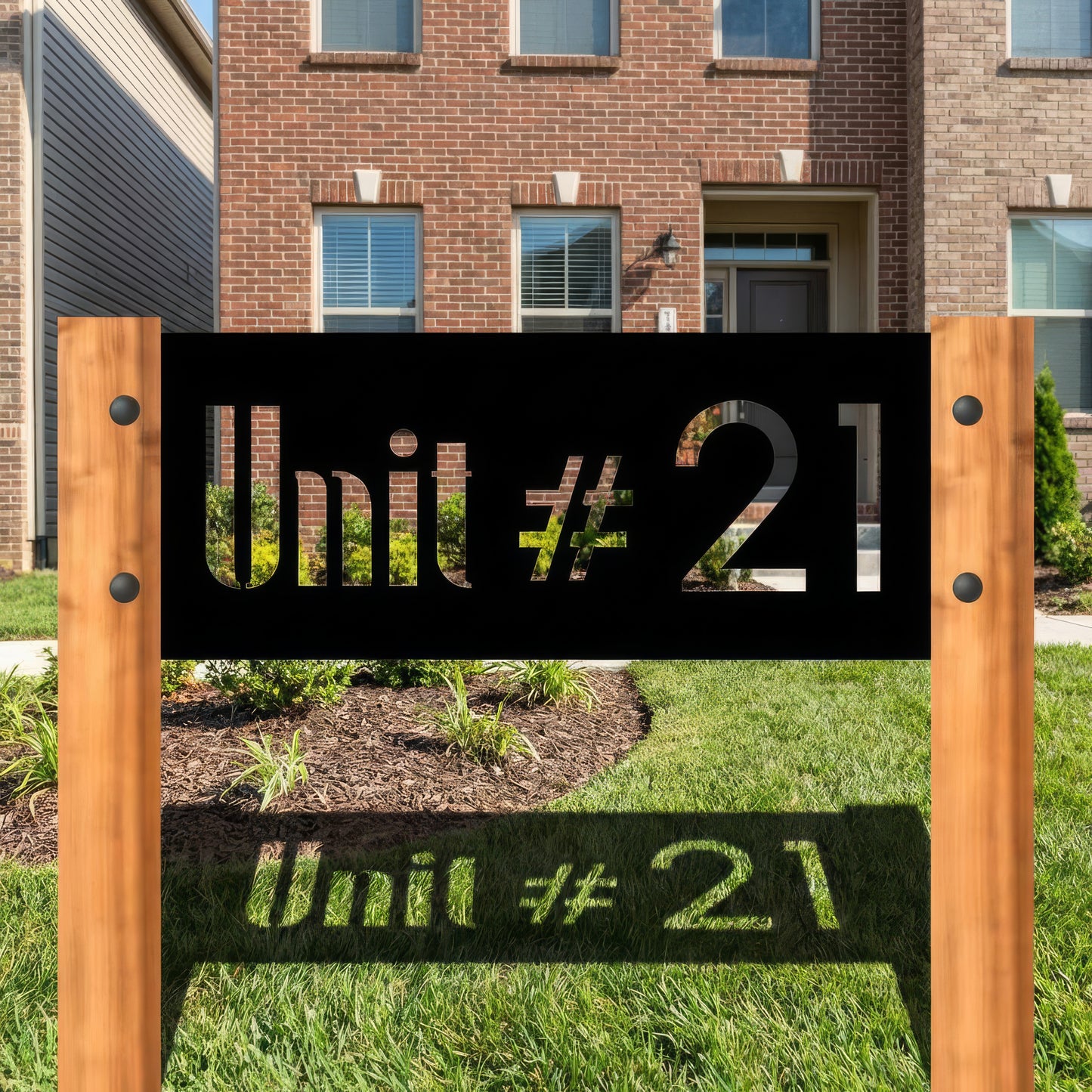 Wooden sign with 'Unit #21' text in front of a brick building.