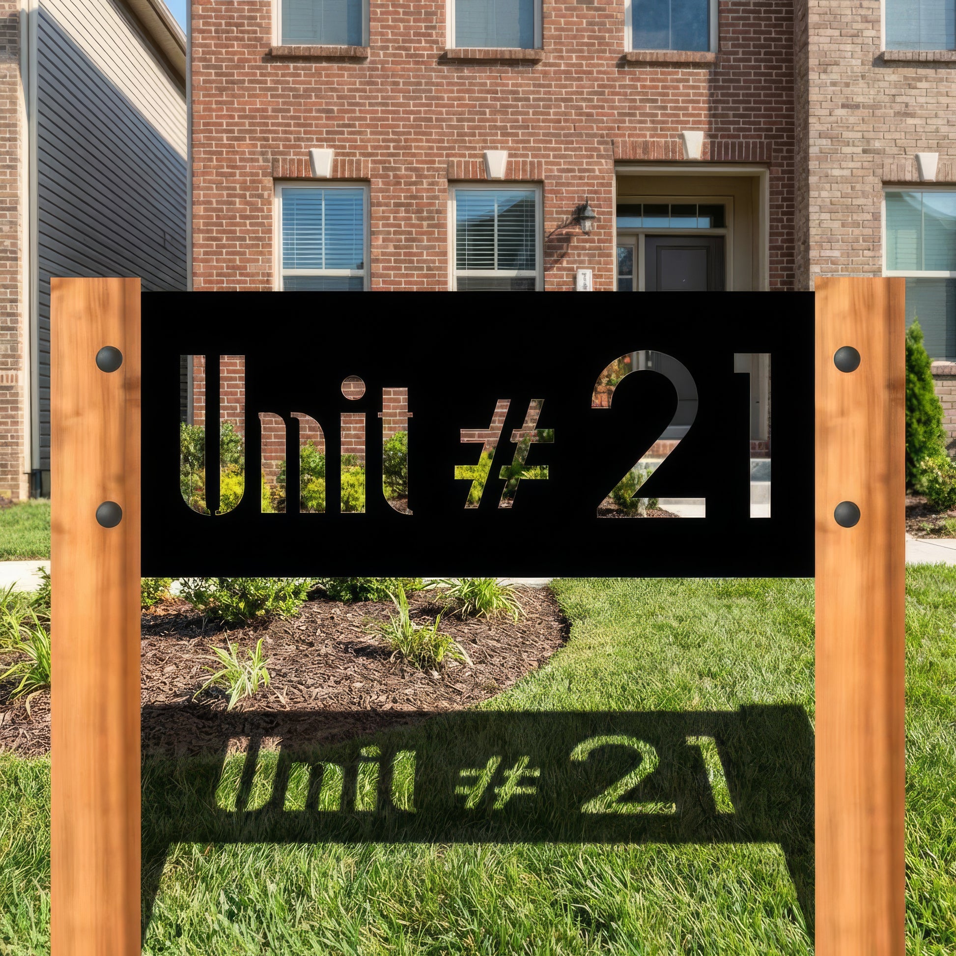Wooden sign with 'Unit #21' text in front of a brick building.