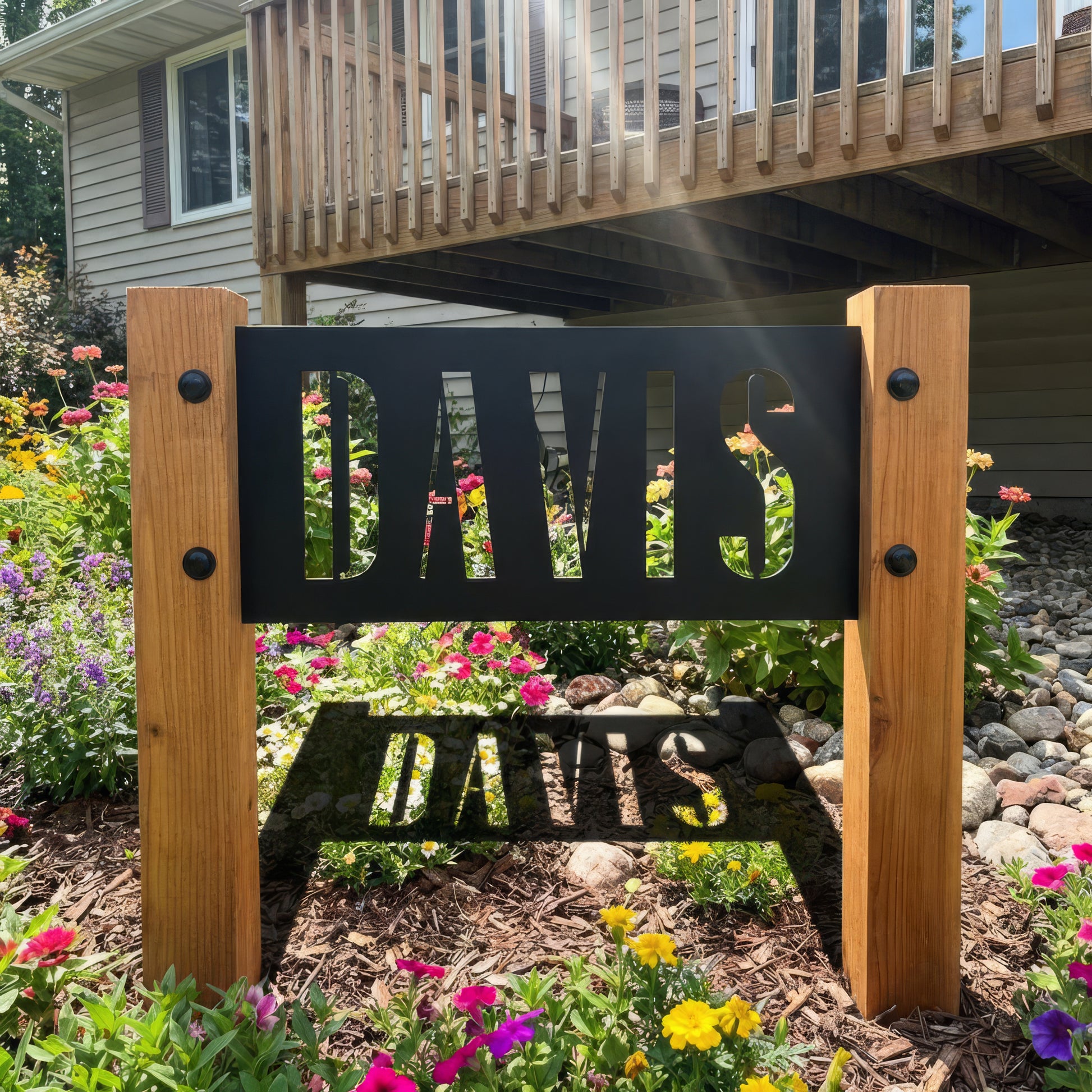 Decorative metal sign with 'DAVIS' on a wooden stand in a garden setting.